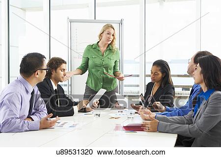 Stock Image - Businesswoman Conducting Meeting In Boardroom. Fotosearch