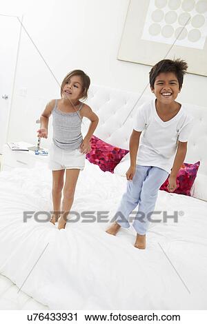 Stock Image - Children Jumping On Bed In Pajamas Together. Fotosearch