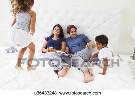 Stock Photo - Children Jumping On Parents Bed Wearing Pajamas. Fotosearch