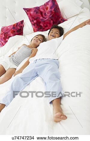 Children Lying On Bed In Pajamas Together View Large Photo Image Picture - Children Lying On Bed In Pajamas Together. Fotosearch