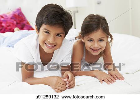 Stock Image - Children Lying On Bed In Pajamas Together. Fotosearch