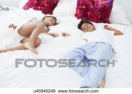 Children Lying On Bed In Pajamas Together View Large Photo Image Stock Photo - Children Lying On Bed In Pajamas Together. Fotosearch