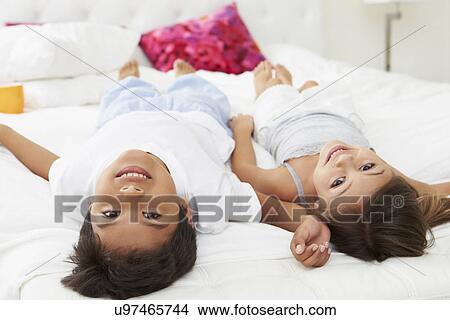 Picture - Children Lying Upside Down On Bed In Pajamas Together. Fotosearch