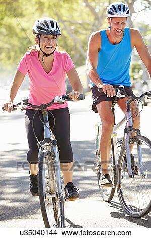 Picture - Couple Cycling On Suburban Street. Fotosearch