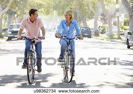 Picture - Couple Cycling On Suburban Street. Fotosearch