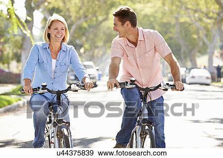 Stock Photo - Couple Cycling On Suburban Street. Fotosearch