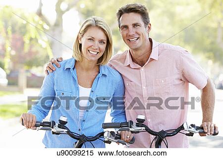Couple Cycling On Suburban Street View Large Photo Image Stock Photography - Couple Cycling On Suburban Street. Fotosearch