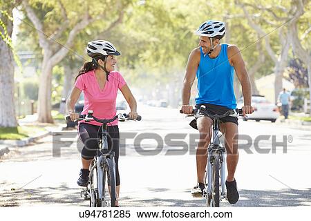 Stock Photography - Couple Cycling On Suburban Street. Fotosearch