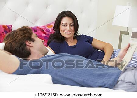 Couple Relaxing In Bed Wearing Pajamas And Reading Newspaper View Large Photo Image Stock Image - Couple Relaxing In Bed Wearing Pajamas And Reading Newspaper. Fotosearch