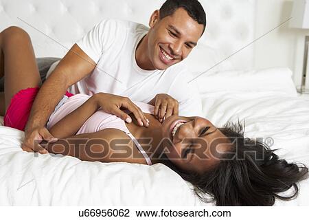 Stock Image - Couple Relaxing In Bed Wearing Pajamas. Fotosearch