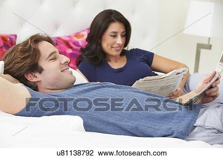 Couple Relaxing In Bed Wearing Pajamas And Reading Newspaper View Large Photo Image Stock Image - Couple Relaxing In Bed Wearing Pajamas And Reading Newspaper. Fotosearch