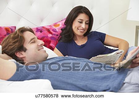 Couple Relaxing In Bed Wearing Pajamas And Reading Newspaper View Large Photo Image Stock Photo - Couple Relaxing In Bed Wearing Pajamas And Reading Newspaper. Fotosearch