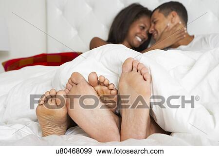 Stock Photo - Couple Relaxing In Bed Wearing Pajamas. Fotosearch