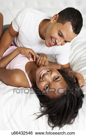 Stock Photograph - Couple Relaxing In Bed Wearing Pajamas. Fotosearch