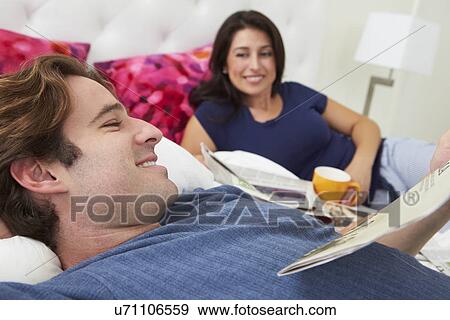 Stock Photo - Couple Relaxing In Bed With Coffee And Newspaper. Fotosearch