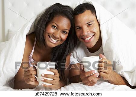 Stock Photo - Couple Relaxing In Bed With Hot Drink. Fotosearch