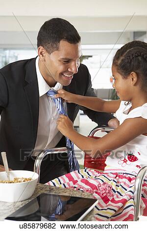 Stock Image - Daughter Straightens Father's Tie Before He Leaves For Work. Fotosearch