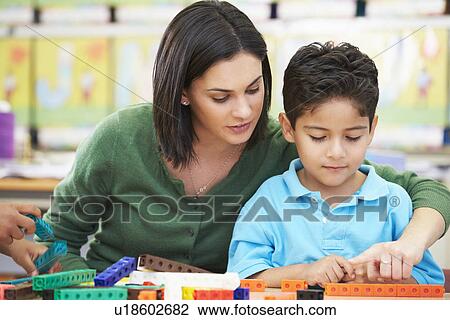 Stock Image - Elementary Pupil Counting With Teacher In Classroom. Fotosearch