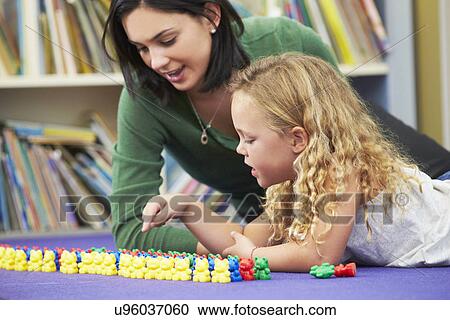 Stock Image - Elementary Pupil Counting With Teacher In Classroom. Fotosearch