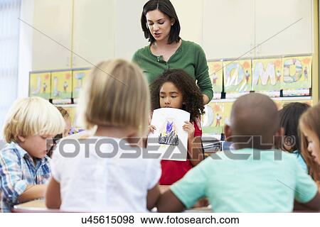 Elementary Pupil Showing Drawing To Classmates In Classroom View Large Photo Image Stock Photo - Elementary Pupil Showing Drawing To Classmates In Classroom. Fotosearch