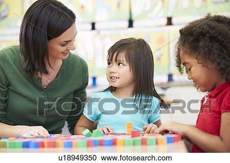 Stock Image - Elementary Pupils Counting With Teacher In Classroom. Fotosearch