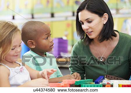 Stock Image - Elementary Pupils Counting With Teacher In Classroom. Fotosearch