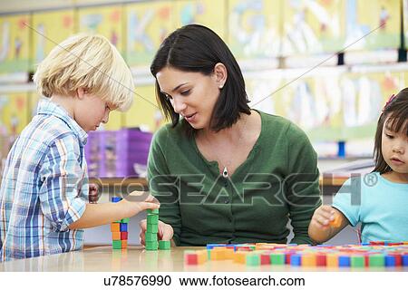 Stock Image - Elementary Pupils Counting With Teacher In Classroom. Fotosearch