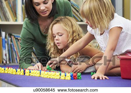 Stock Photography - Elementary Pupils Counting With Teacher In Classroom. Fotosearch