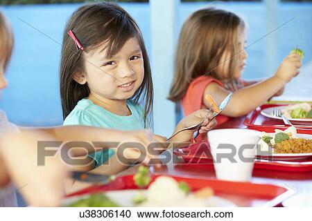 Stock Image - Elementary Pupils Enjoying Healthy Lunch In Cafeteria. Fotosearch