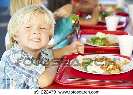 Stock Photo - Elementary Pupils Enjoying Healthy Lunch In Cafeteria. Fotosearch