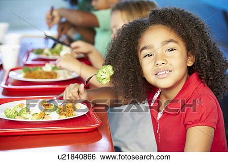 Stock Photograph - Elementary Pupils Enjoying Healthy Lunch In Cafeteria. Fotosearch