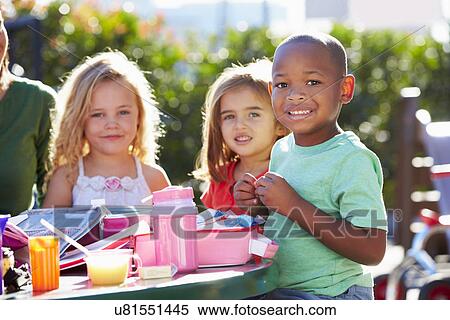 Stock Photography - Elementary Pupils Sitting At Table Eating Lunch. Fotosearch
