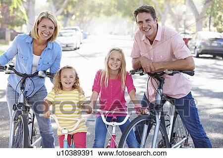 Stock Image - Family Cycling On Suburban Street. Fotosearch