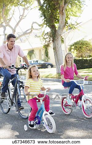 Stock Image - Family Cycling On Suburban Street. Fotosearch