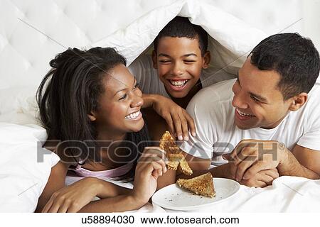 Stock Image - Family Enjoying Breakfast In Bed. Fotosearch