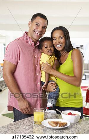 Stock Image - Family Having Breakfast In Kitchen Together. Fotosearch
