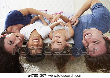 Stock Photo - Family Lying Upside Down On Bed In Pajamas Together. Fotosearch
