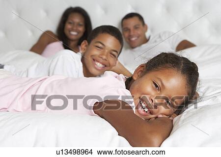 Picture - Family Relaxing In Bed Together. Fotosearch