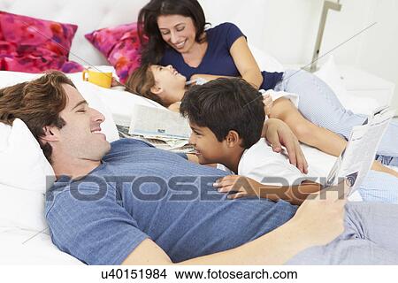 Picture - Family Relaxing In Bed With Coffee And Newspaper. Fotosearch
