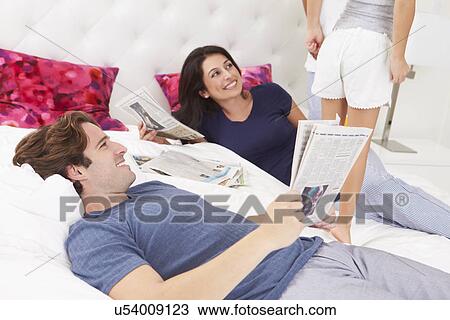 Stock Image - Family Relaxing In Bed With Coffee And Newspaper. Fotosearch