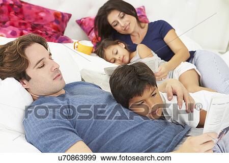 Stock Photo - Family Relaxing In Bed With Coffee And Newspaper. Fotosearch