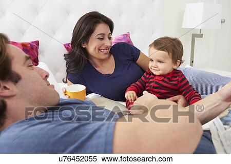 Stock Photography - Family Relaxing In Bed With Coffee And Newspaper. Fotosearch