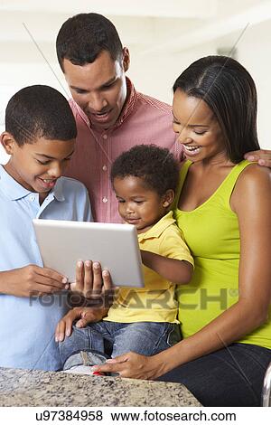 Stock Photo - Family Using Digital Tablet In Kitchen Together. Fotosearch