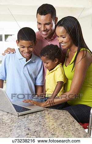 Stock Photograph - Family Using Laptop In Kitchen Together. Fotosearch