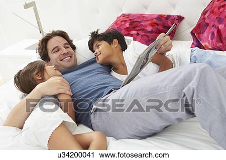 Father And Children Relaxing In Bed Together View Large Photo Image Stock Image - Father And Children Relaxing In Bed Together. Fotosearch