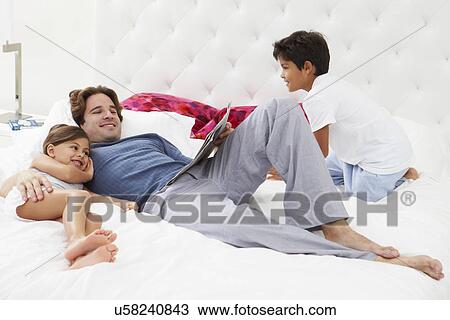Father And Children Relaxing In Bed Together View Large Photo Image Stock Image - Father And Children Relaxing In Bed Together. Fotosearch