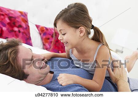 Stock Image - Father And Daughter Lying In Bed Together. Fotosearch