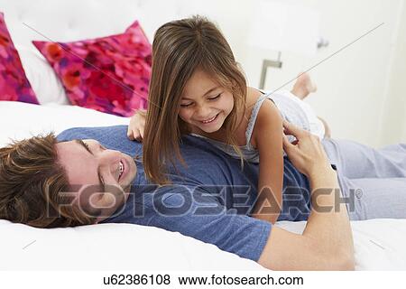 Stock Photo - Father And Daughter Lying In Bed Together. Fotosearch