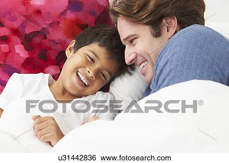 Stock Photograph - Father And Son Lying In Bed Together. Fotosearch
