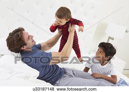 Stock Photo - Father Playing In Bed With Children. Fotosearch
